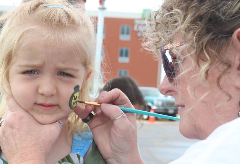 Emma Meskee has her face painted by Bren Dazions during the Cars and Coffee Car Show on Sunday,  July 14, 2024 at Bill Walsh Kia and Ford in Ottawa.