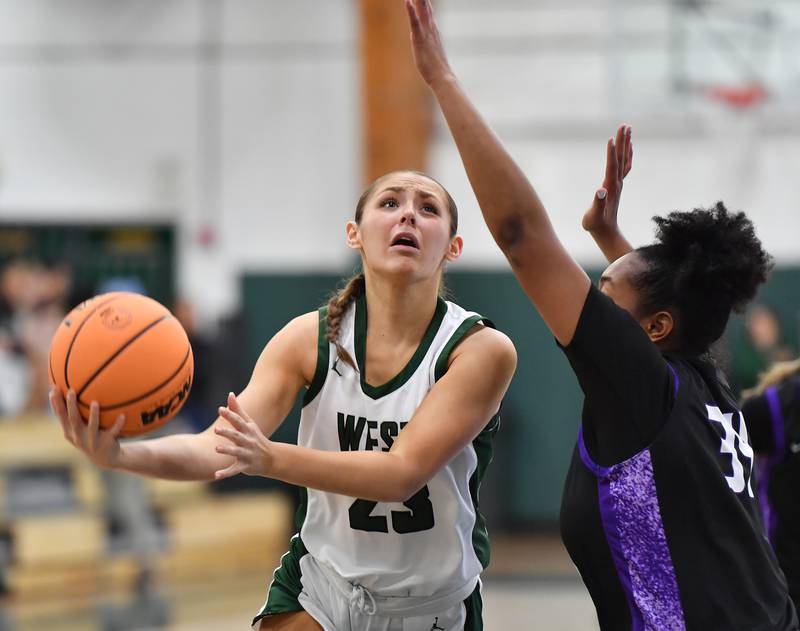 Glenbard West’s Mya Austin lays the ball up for the first points of the game as Downers Grove North’s Elizabeth Murphy defends on December 4, 2025 at Glenbard West High School in Glen Ellyn.
