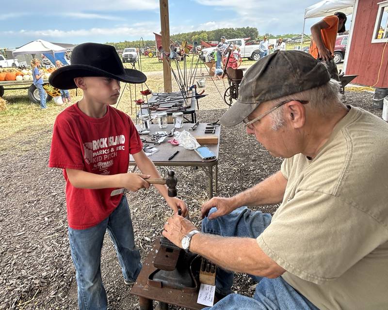 Nolan Huber, 9, of Milan, makes a metal stamp with his initials on it under the direction of Daryl Drennen of Prophetstown at the Bos Bros. Historical Farm Old Fashioned Fall Harvest south of Erie on Springhill Road Saturday, Sept. 21, 2024. Hands-on demonstrations gave kids the opportunity to try a variety of trade skills.