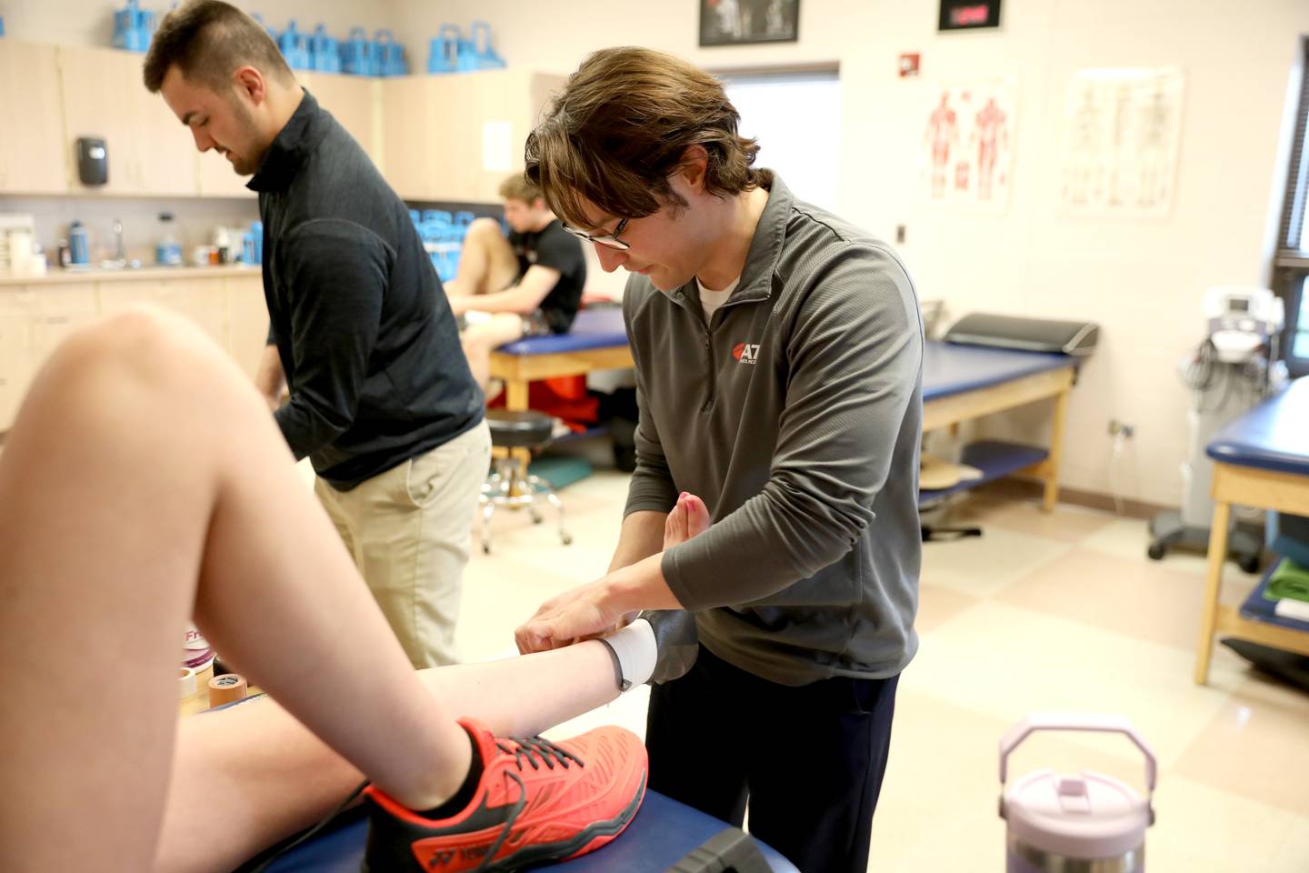 St. Charles North Athletic Trainer Zach Zinzer tapes an athlete’s ankle at the school.