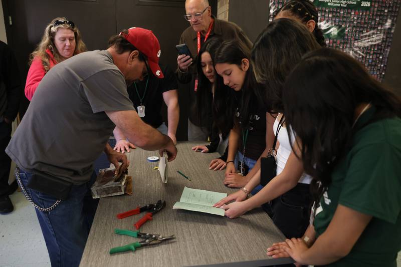 Grompers Junior High School students look over items that were found in a time capsule as Randy Williams removes more items on Wednesday, May 1, 2026 in Joliet. In 1969 students placed items in a time capsule and sealed it inside a wall when an extension was built at Grompers Junior High School.
