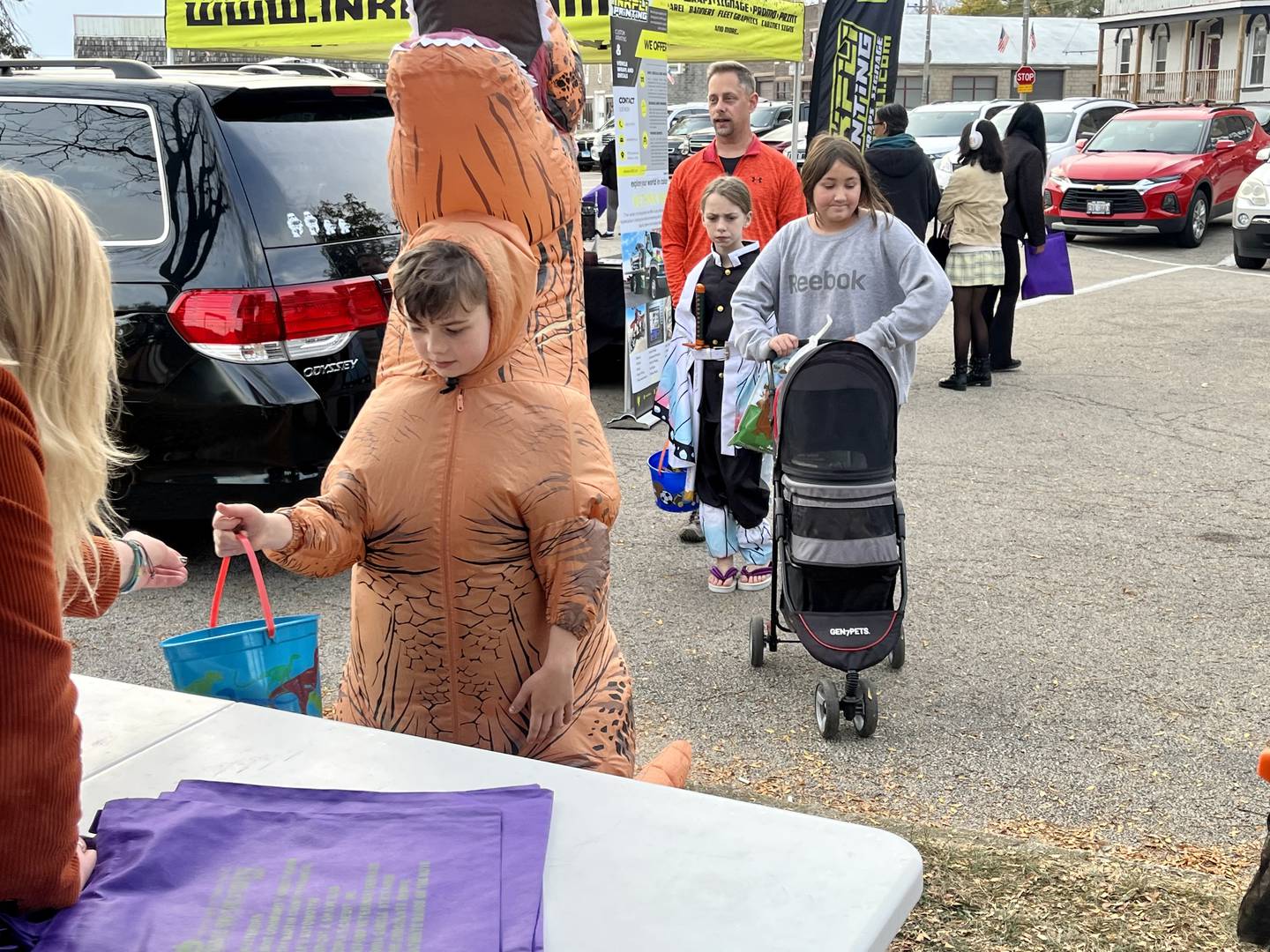 A costumed tyrannosaurus collects candy from a local business in Plano's downtown Halloween event.