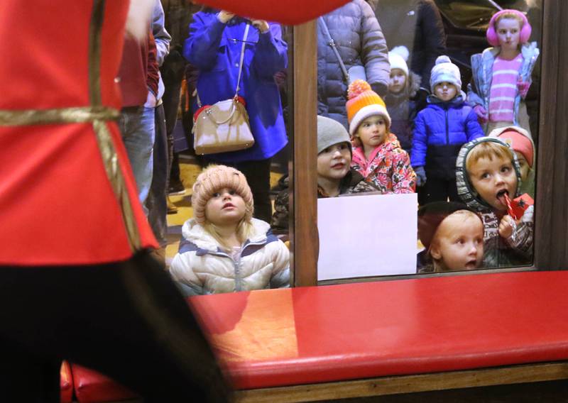 Kids peer through the window of Pizza. Beer. Whiskey. to watch a scene from “The Nutcracker” play out Friday, Nov. 22, 2024, during Moonlight Magic in downtown Sycamore.