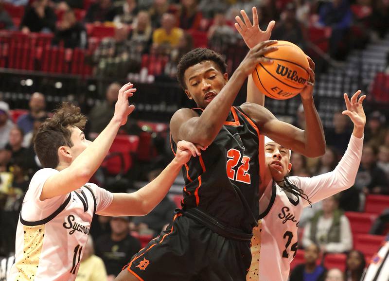 DeKalb's Justin O’Neal grabs a rebound between Sycamore's Jake Shipley (left) and Unique Shaw during their game Friday, Jan. 31, 2025, in the FNBO Challenge in the Convocation Center at Northern Illinois University in DeKalb.