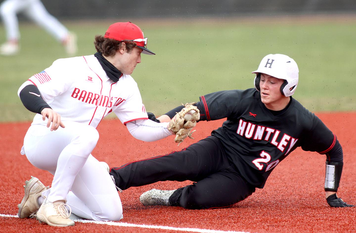 Barrington’s Michael Audino, left, prepares to apply a tag as Huntley’s Haiden Janke arrives safely at third base in varsity baseball at Barrington Saturday.