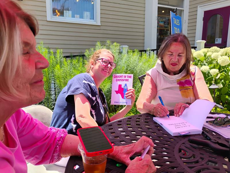 Geneva author Ellen Jo Ljung, (right) signs a copy of her first novel, 'Caught in the Crossfire,' for Vadie Schultz, (far left) on Saturday, June 28, at Harvey's Tales in Geneva. She also signed a book for Cristine Clemente Dos Santos (center) also of Geneva. Ljung's book is about a progressive teacher  who lands in the middle of Texas politics in the 2022-23 school year.