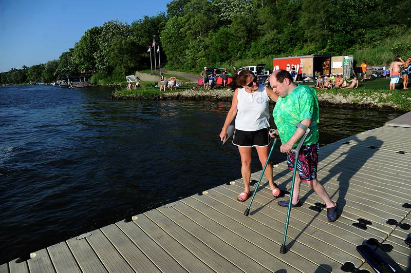 Janet Carran talks with Erik Hoary as he heads out to a boat for his water ski performance Tuesday, June 21, 2022, in the Wonder Lake Water Ski Show Team and Northern Illinois Special Recreation Association’s show on Wonder Lake. The performance was the end of the team’s learn to ski clinic. Members of ski team have constructed adaptive water ski equipment, which has proven year after year to be successful in allowing every participant to be able to water ski.