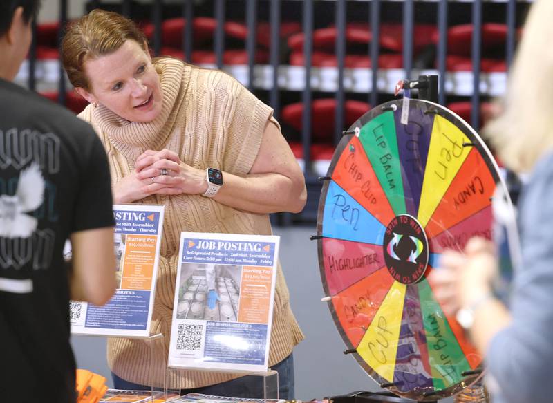 Ashley Murcia, from the Suter Company, watches as a visitor spins the wheel at their booth Thursday, April 23, 2026, during the DeKalb Chamber of Commerce Local Showcase in the Convocation Center at Northern Illinois University in DeKalb.