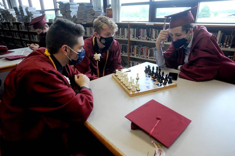 Kyle Denzel, right, ponders his move as he and Connor Lindsey, center, play chess with Leland Robinson, left, Sunday afternoon, May 23, 2021, before the first of two commencement ceremonies at Richmond-Burton Community High School in Richmond. More than 130 students took part in the school’s graduation ceremony in the school’s gym.