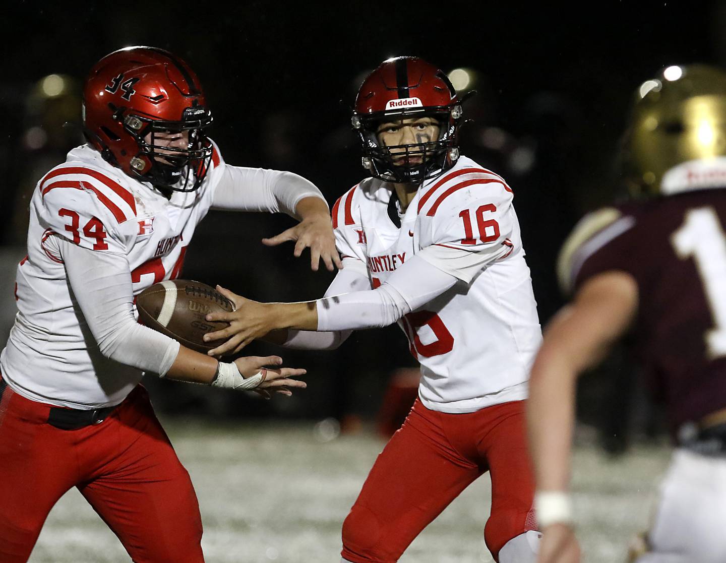 Huntley's Braylon Bower hands the ball off to running back Haiden Janke during a IHSA Class 8A second round playoff football game against St. Ignatius on Friday, Nov. 3, 2023, at St. Ignatius College Prep in Chicago.