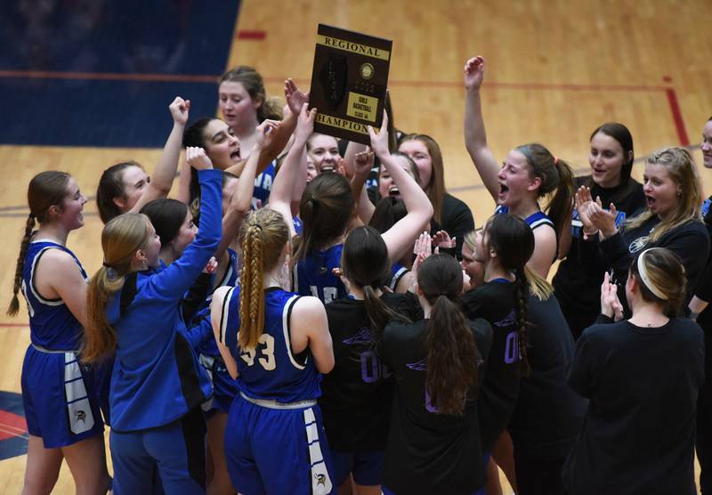 The Geneva players celebrate around the IHSA Class 4A girls basketball regional championship plaque after defeating Conant Friday in Hoffman Estates.