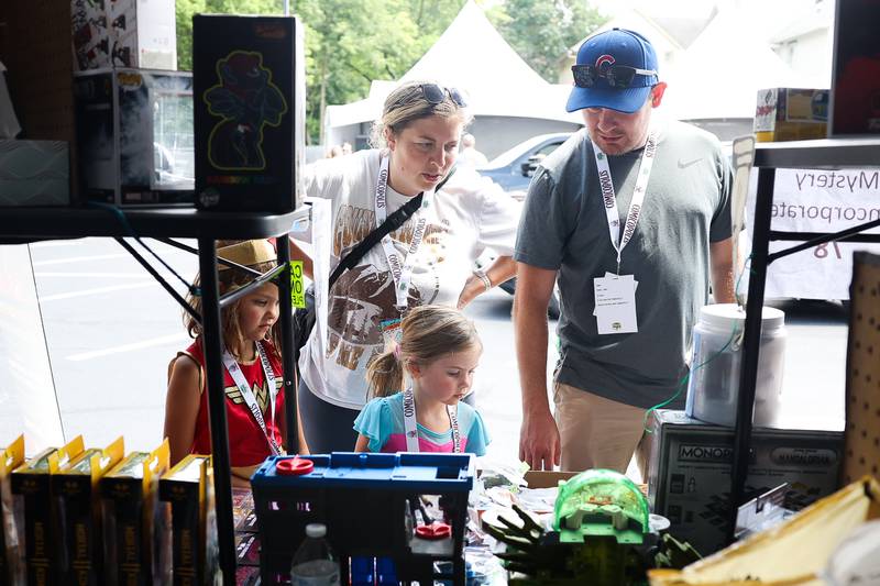 The Mucha family, Lindsey, top left clockwise, Tim, Finley and Lucy look over merchandise at one of the many tents at Comicolopis, Lockport’s 7th annual Comic and Fandom Con on Saturday, July 29.