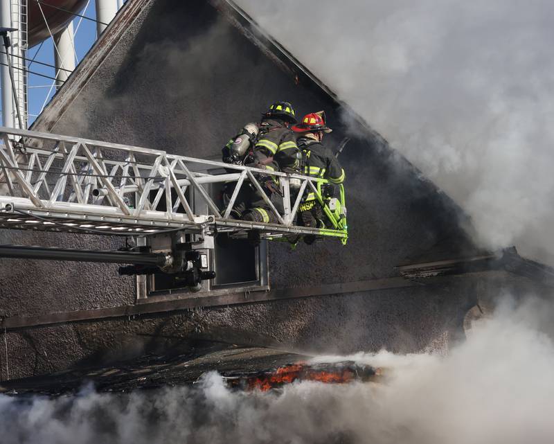 Firefighters position the Peru aerial ladder truck at the top of the attic of a buring structure fire in the 800 block of Bucklin Street on Friday, Jan. 23, 2026 in La Salle.