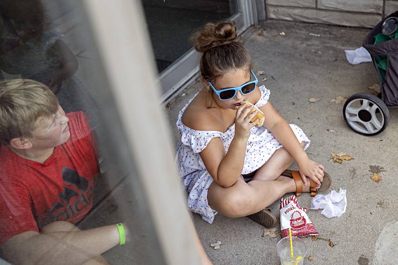 Jane Miles, 8, digs into a dog Friday, August 4, 2023 outside of Airplay in Sterling. Sterling Main Street’s Hot Dog Days continues a tradition over 40 years old with the lunch time favorite being made at business’ and booths all over the city.