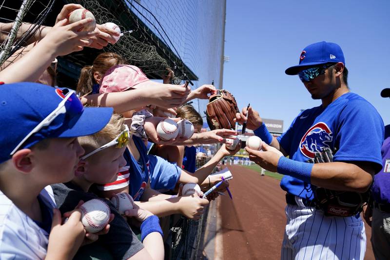 Chicago Cubs outfielder Seiya Suzuki signs autographs for fans prior to a spring training game against the Chicago White Sox on April 4, 2022, in Mesa, Ariz.