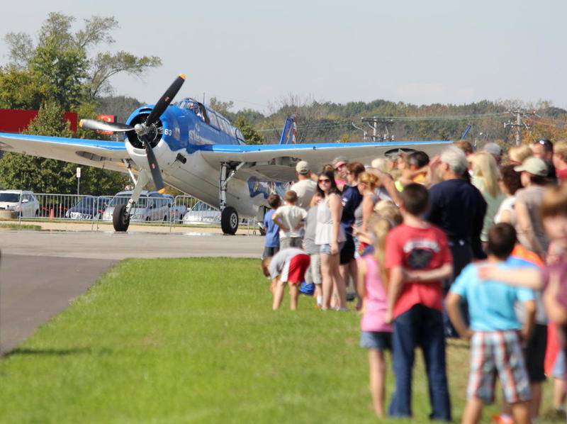 Aviation enthusiasts gather at the side of the runway to watch Tom Buck of Joliet fly his TBM Avenger at the 2014 Joliet Airport Festival.