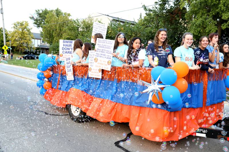 Wheaton Warrenville South swimmers ride atop a float during the school’s annual homecoming parade on Wednesday, Sept. 11, 2024 on Weisbrook Road in Wheaton.