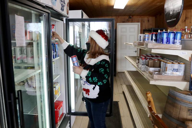 General Store employee Sharon Consentino stocks a beer fridge Tuesday, Dec. 15, inside a section of the Greenwood store, which used to serve as the township's post office.  The building has been a general store since its construction in 1894.
