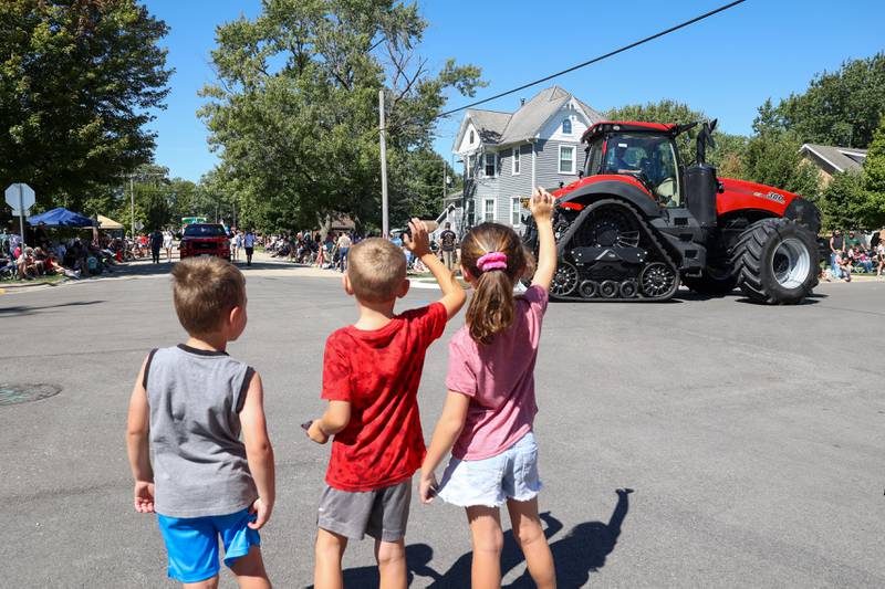 Three young paradegoers wave to a passing farm vehicle during the 104th annual Herscher Labor Day Celebration on Monday, Sept. 1, 2025.
