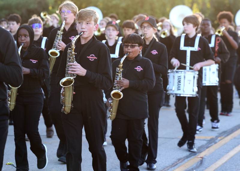 Members of the Huntley and Clinton Rosette J-Barbs marching band make their way down West Dresser Road Wednesday, Oct. 2, 2024, during the DeKalb homecoming parade.