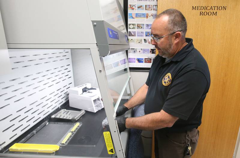 La Salle County Corner Rich Ploch, uses a filter balancing containment hood to sort through medication at the La Salle County Forensic Center on Wednesday, Aug. 30, 2023, in Oglesby. The hood balances exposures of fumes and other particulates containing powders and removes toxic particulate and other matter when handling the material. State statute requires coroners to collect and store controlled substances from death scenes. These materials can be toxic so the hood ensures safe handling.