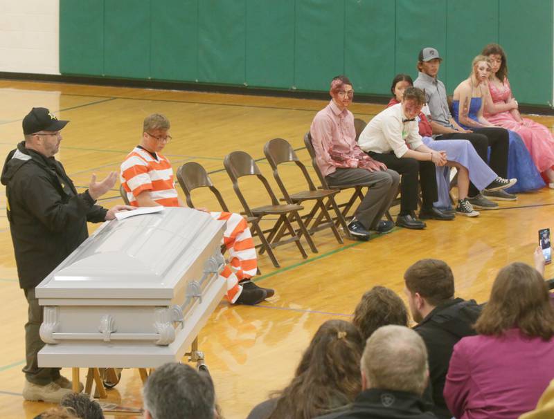 La Salle County Coroner Rich Ploch, delivers a message to students in the gymnasium during a Mock Prom funeral Leland High School on Friday, May 6, 2022 in Leland. A casket was brought into the gymnasium during the mock drill to show students how making bad choices on prom night can lead to fatal accidents.