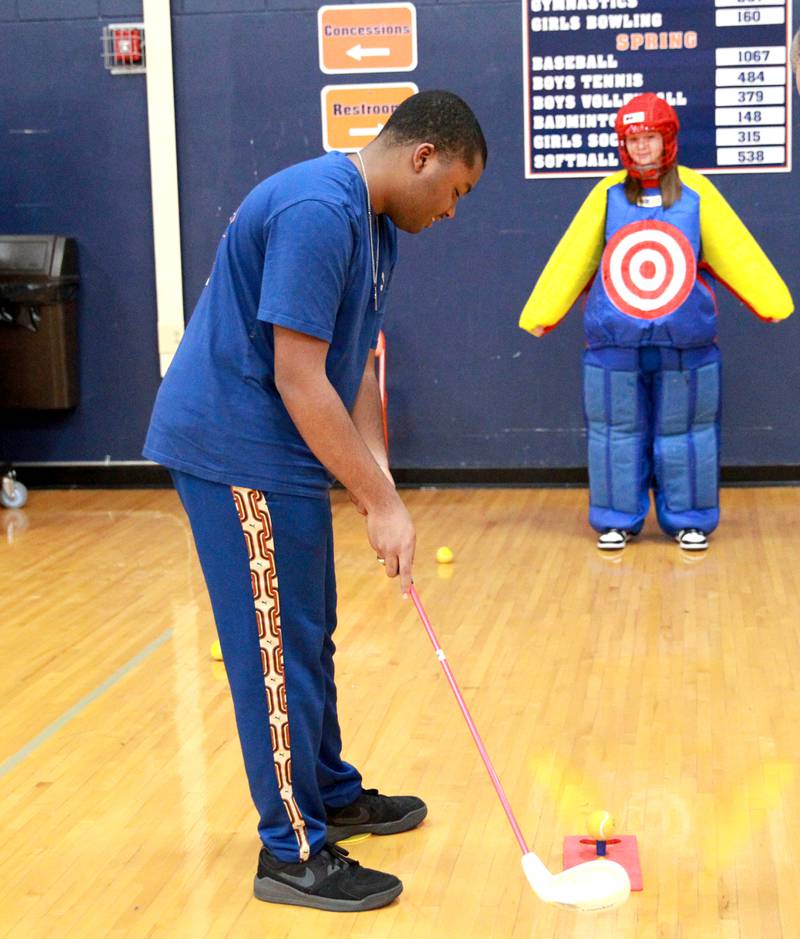 Oswego High School student Bradon Boykins tees up his golf shot at classmate Madi Dietz during their physical education class at Oswego High School on Monday, March 4, 2024. The class was part of a six-week program collaboration with the U.S. Adaptive Golf Alliance.