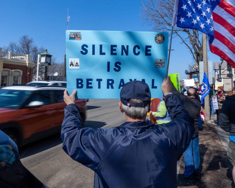 Protester holds sign as cars drive down La Salle St. during the 'Pretti good time for a Protest' on Feb. 15, 2026 at Washington Square Park in Ottawa.