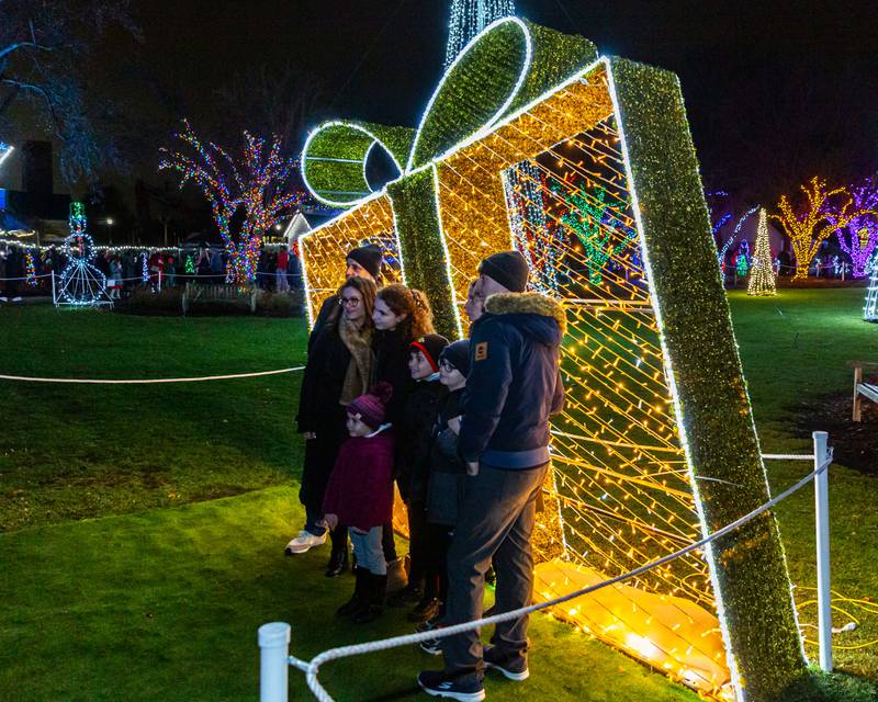 A family pose for a picture in front of  lighted package display at the Lombard Jingle Bell Jubilee. Dec 2, 2023