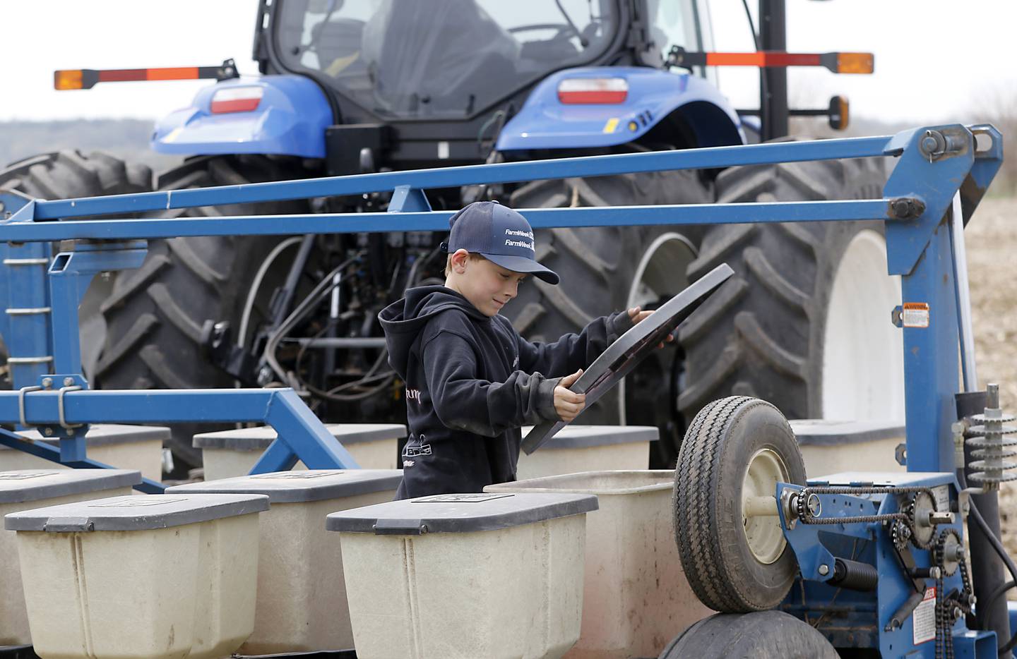 Clayton McKee looks in a seed bin on Friday, April 28, 2023, as he helps his dad, Chris, to plant soybeans near Woodstock.