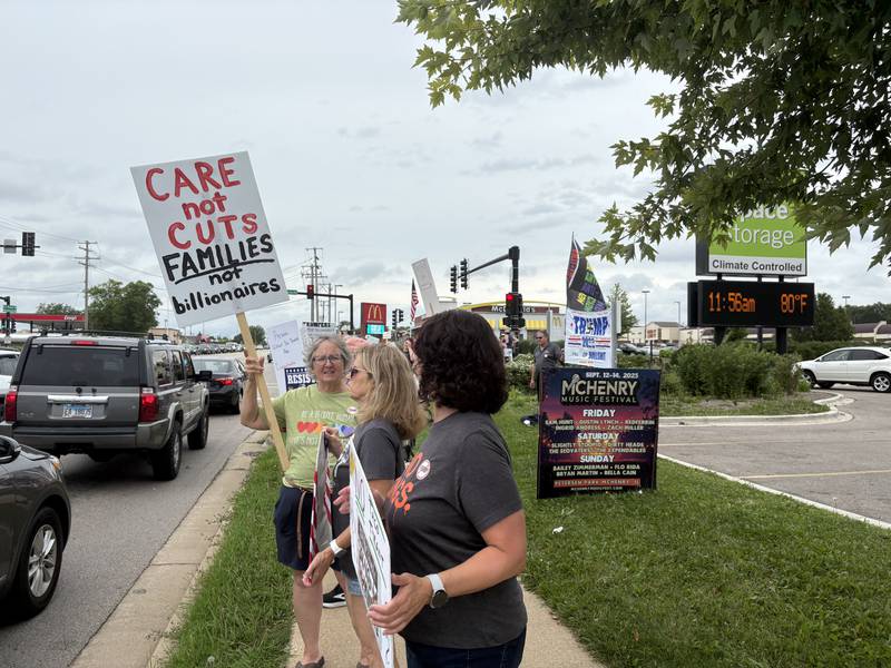 Protesters hold up signs during 
a protest against President Trump in McHenry July 26, 2025.