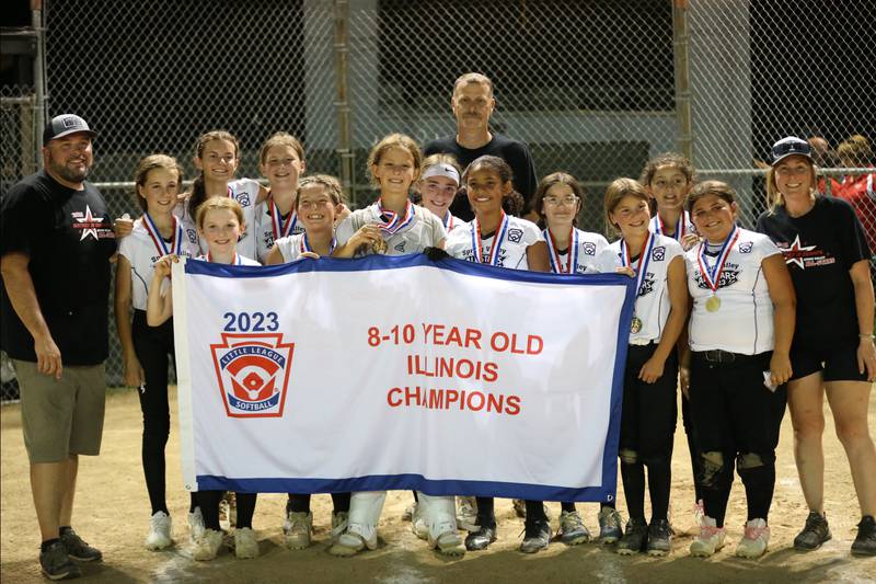 Members of the Spring Valley softball team pose with their championship banner after defeating Evergreen Park in the Minor League Softball State title on Thursday, July 27, 2023 at St. Mary's Park in La Salle.