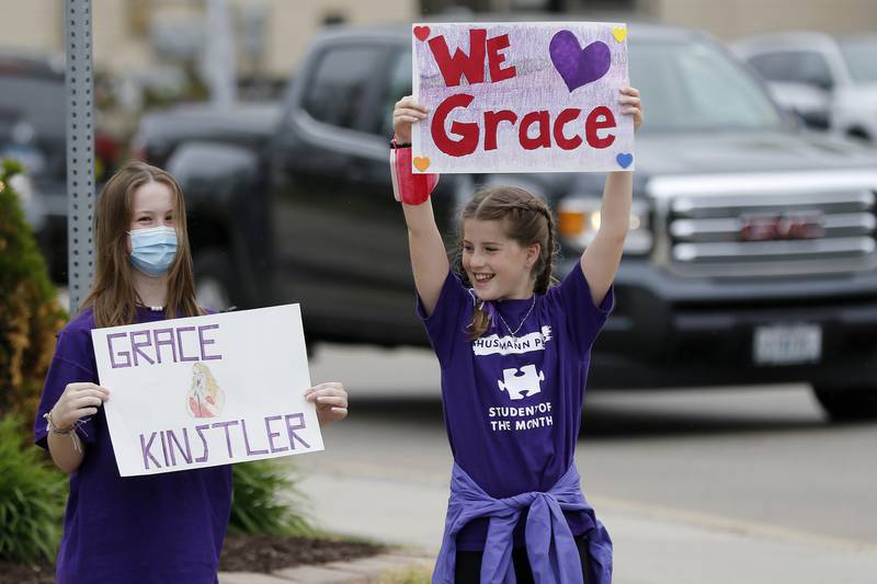 Grace Fujino, 13, left, and sister Gabrielle Fujino, 10, both of Crystal Lake, hold up signs in support of Grace Kinstler, a Crystal Lake Central High School graduate and finalist on "American Idol," as they await a parade through downtown on Tuesday, May 18, 2021, in Crystal Lake.