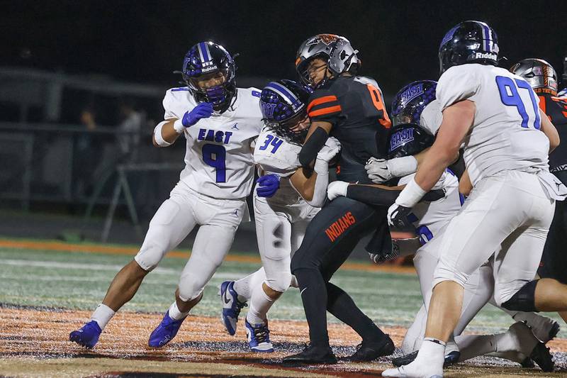 Lincoln-Way East’s Miko Moraga (9) and Charlie Palmer (34) wrap up Minooka’s Paris Spears for no gain on Friday, Nov. 8, 2024 in Minooka.