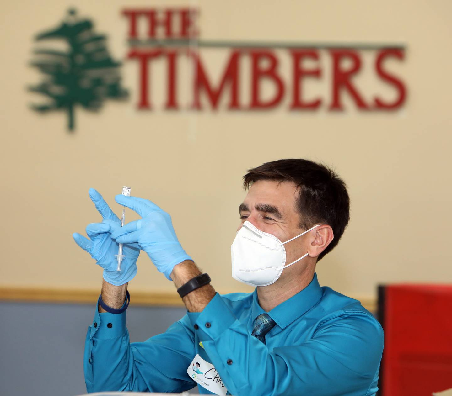 Chad Kodiak of KODOCARE pharmacy fills a syringe with the COVID-19 booster vaccine as Timbers of Shorewood staff and residents line up to receive the flu and COVID-19 vaccine Friday, October 8, 2021, in Shorewood, Ill.