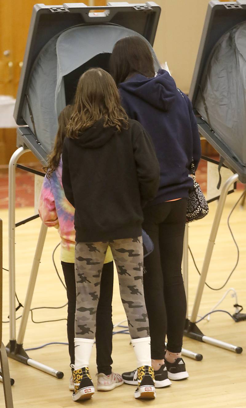 Alexa Hoving, 7, of Hampshire, and her sister, Julia, 11, watch as their mother, Katie, casts her vote Tuesday, April 4, 2023, in the 2023 consolidated election at Del Webb Sun City’s Prairie Lodge in Huntley.