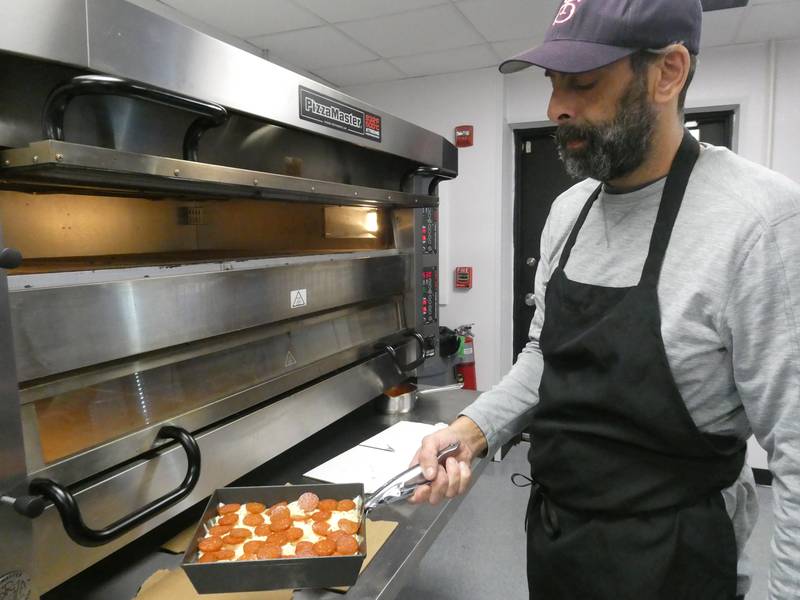 Co-owner Harry Canelos prepares to cook a Detroit-style pepperoni pizza inside the kitchen at Pizza Pushers, a new joint in Algonquin that specializes in Motor City offerings.