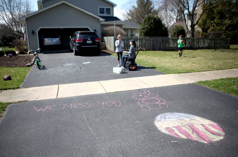 Siblings Emma, 10, and Nolan Falkos, 8, with mom Melissa, made chalk drawings on their Batavia driveway as they waited for their grandparents to drive by as Kane County residents continue to practice social distancing during the state's stay-at-home order due to the coronavirus pandemic.