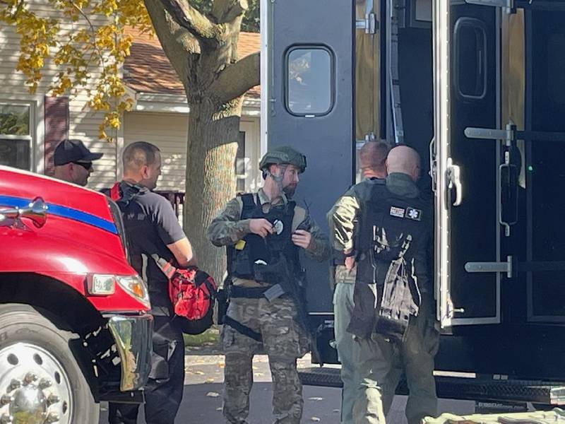A special weapons and tactical team dons gear near an unmarked command van that has arrived on the scene of a standoff between a suspected gunman and law enforcement on Saturday, Oct. 22, 2022, in Sheridan.