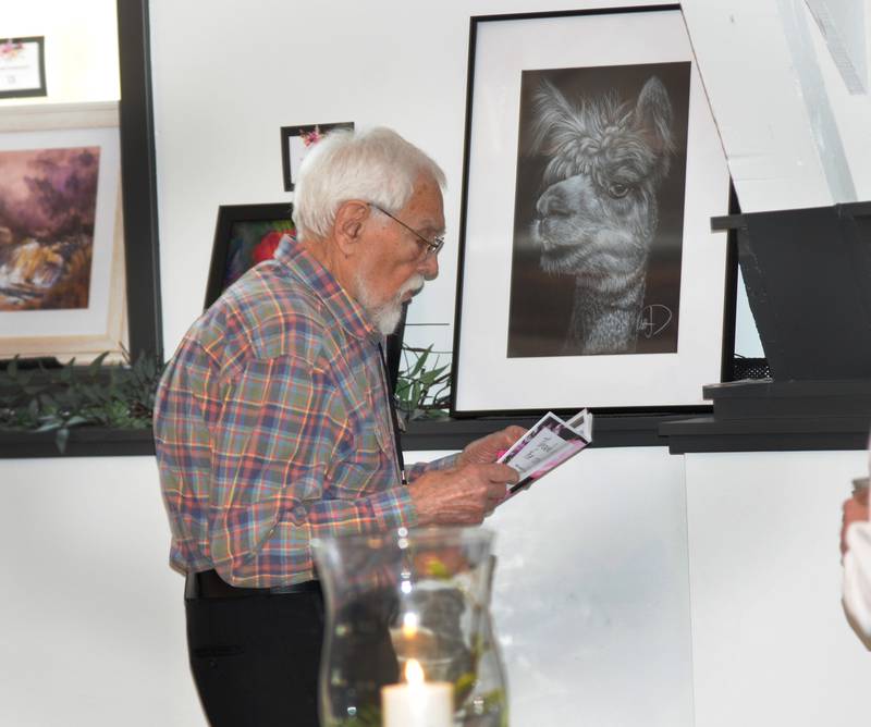 Joe Popp of Oregon looks over the art catalog at the Art Dash, a fundraiser for Serenity Hospice & Home on Wednesday, April 10, 2024 at River's Edge in Oregon.