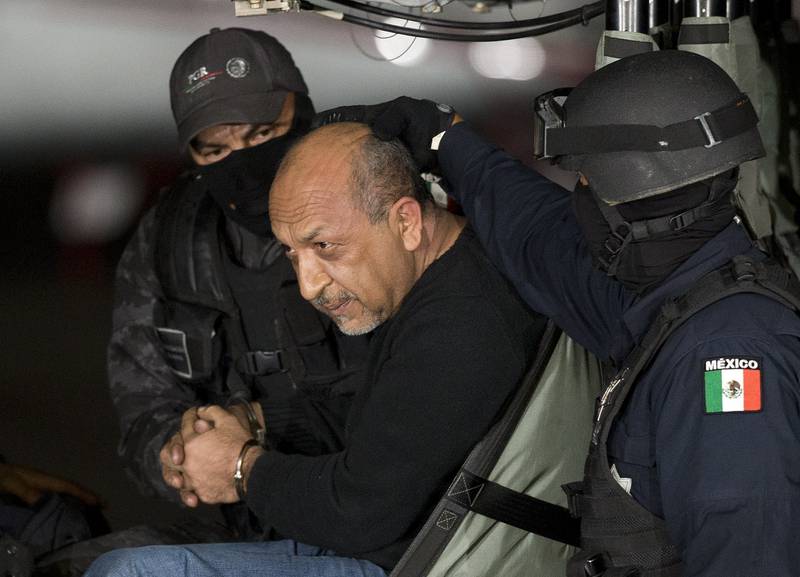 FILE - Mexican federal police escort who they identify as Servando "La Tuta" Gómez," leader of the Knights Templar cartel, as he sits inside helicopter at a Federal hanger in Mexico City, Feb. 27, 2015. (AP Photo/Eduardo Verdugo, File)