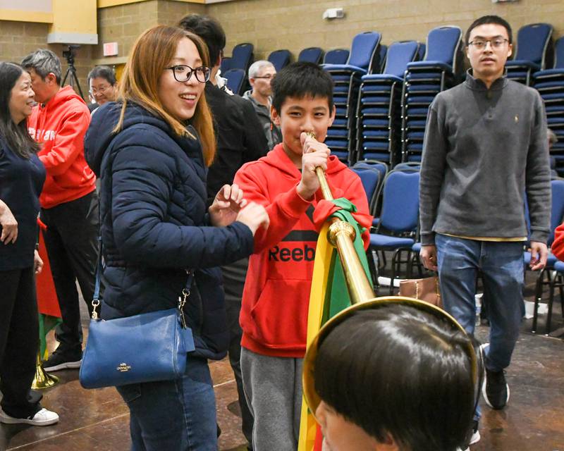 Evette Lim, mom, of Schaumburg  stands by as her son Jace Tan, 11, almost tries the long trumpet as his brother Othniel Tan, 6, puts his ear up to the bell on Saturday April 19, 2025, as community members get to try the instruments after the performance of the Jhong Jheng Elementary School Suona and Drum Ensemble from Kinmen, Taiwan, held at the Taiwanese American Chamber of Commerce building in Westmont.