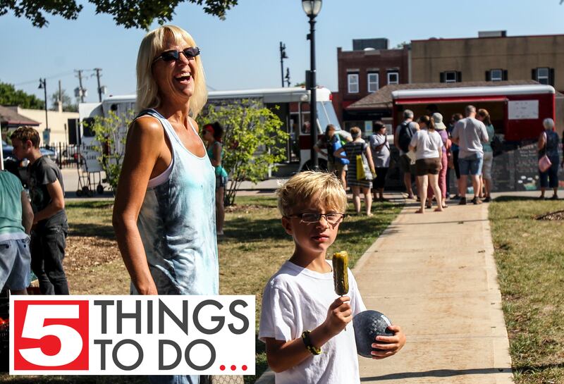 Stacy Ormsby (left) of Crystal Lake and her son, Ethan, 7, walk around the Crystal Lake Farmers Market on Saturday, Aug. 24, 2013, after buying a pickle of a stick at Summer Field's pickle stand at Depot Park.