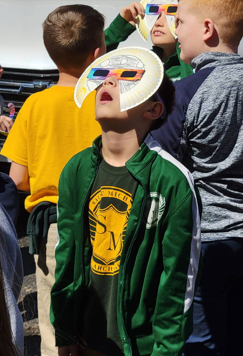 One of the 159 students from St. Michael the Archangel Catholic School in Streator uses his special paper plate glasses to see Monday's solar eclipse.