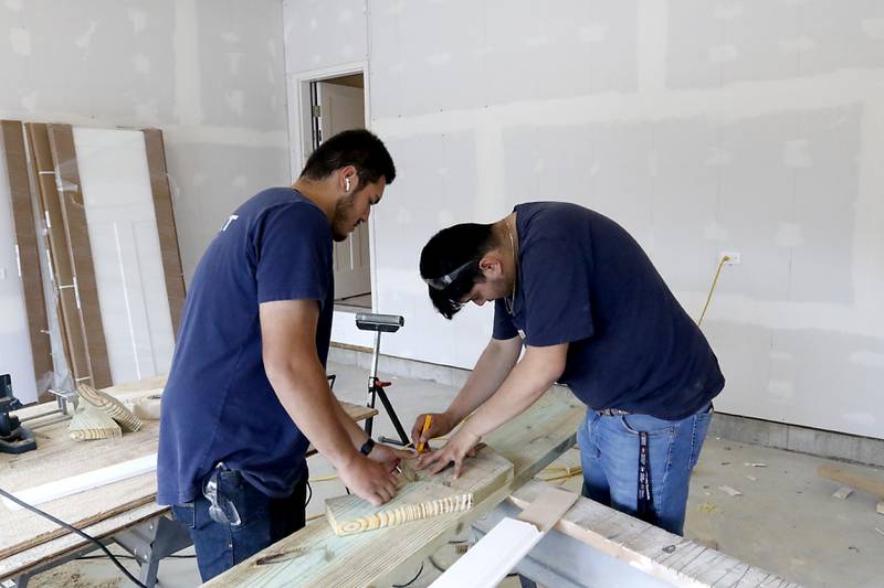 Jose Campos and Erik Moctezuma, both seniors in the Woodstock Building Trades Program, layout stair stringers as they work on building stairs Monday, May 8, 2023, at the home they are building in Woodstock. This will be the program's 43rd completed home since it began in 1972.