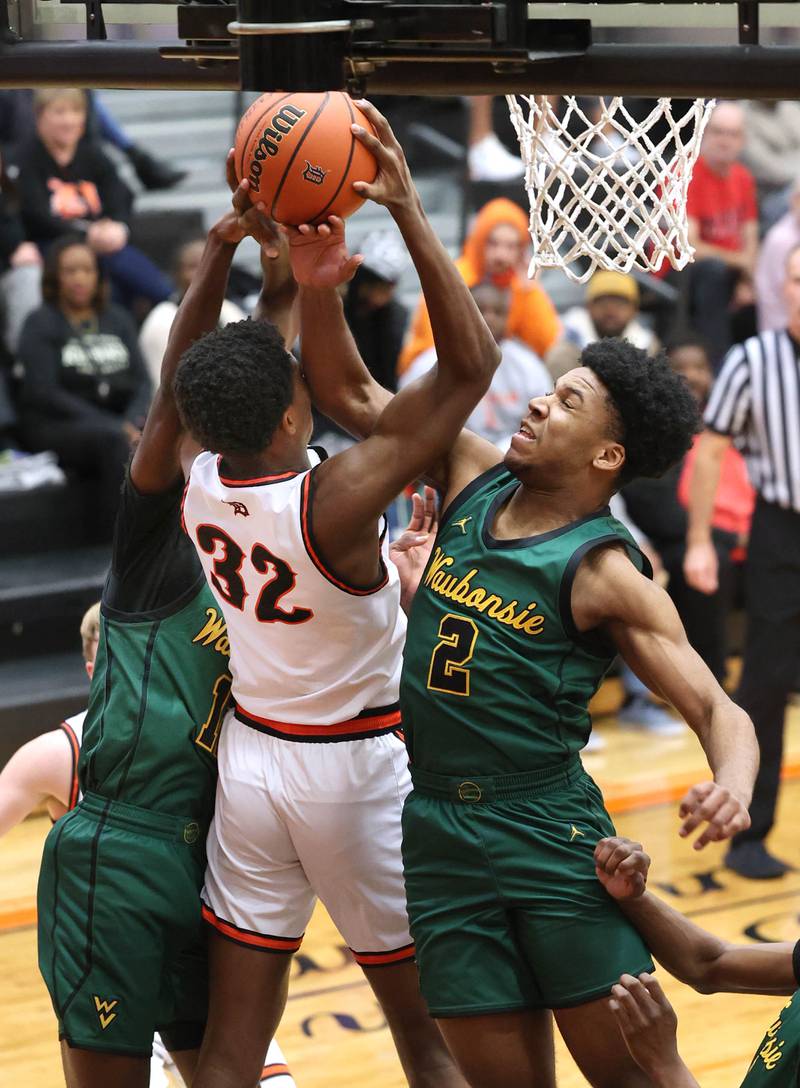 DeKalb’s Justin O’Neal tries to grab a rebound between Waubonsie Valley's Tyreek Coleman (left) and Tyler Threat during their game Friday, Dec. 15, 2023, at DeKalb High School.