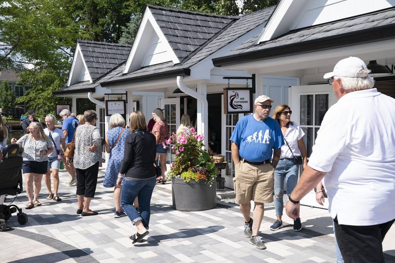 Shoppers explore the new collection of tiny shops at the grand opening and ribbon cutting of the new McHenry Riverwalk Shoppes in downtown McHenry on Friday, July 21, 2023. Ryan Rayburn for Shaw Local