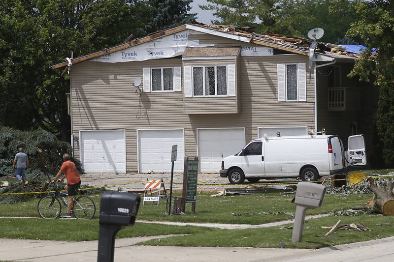 A woman walks past a damaged apartment building in Huntley on Thursday, July 13, 2023, after a confirmed tornado took the roof off the building in Huntley on Wednesday.