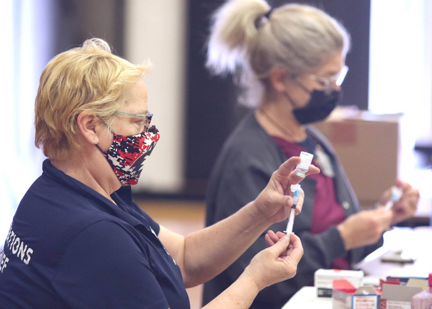 The late Cindy Graves, (left) operations chief for the DeKalb County Health Department's mass vaccination clinic, and public health nurse Kerri Donahue fill syringes with COVID-19 vaccine during the clinic Thursday at Sandwich High School. Graves died May 22, 2022 at Kishwaukee Hospital in DeKalb.