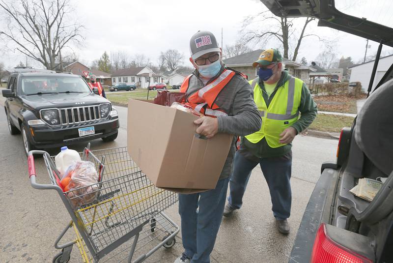 Mike Abrams, and Vito Dalzot, load food into the back of a car for the Hall Township Food Pantries annual Christmas distribution at the food pantry on Wednesday Dec. 15, 2021 in Spring Valley.